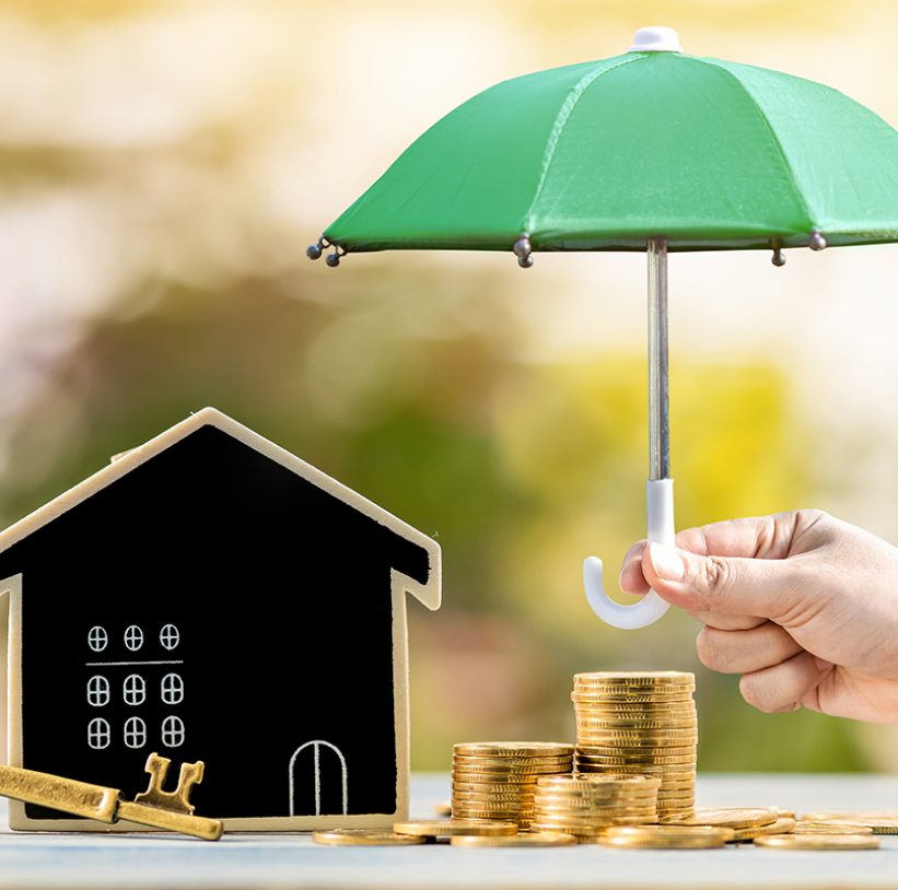 Blackboard house and stacked gold coin and master key and woman hand hold the black umbrella for protect on sunlight in the public park, Saving money for real estate and property protection concept.